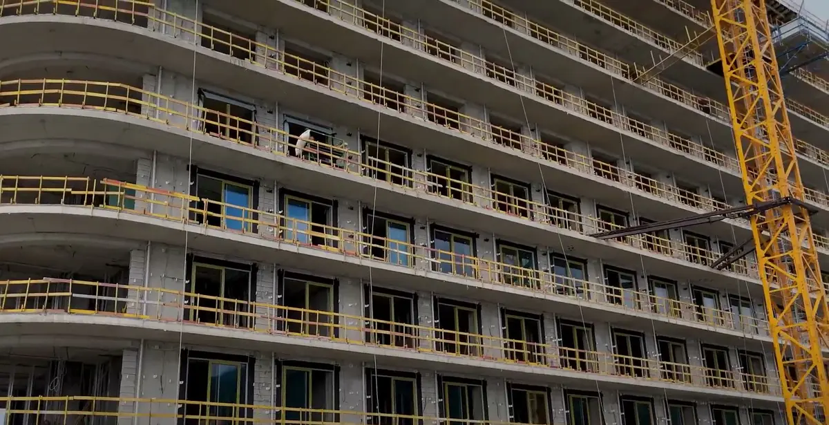 The facade with its rounded balconies and the glazing already fitted, August 2026