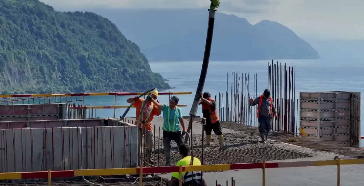Concreting the upper slab, with the Gonio cape and the mountains behind