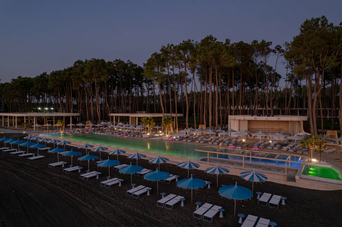 The club pool and the black sand beach at dusk, drone photo of October 2025