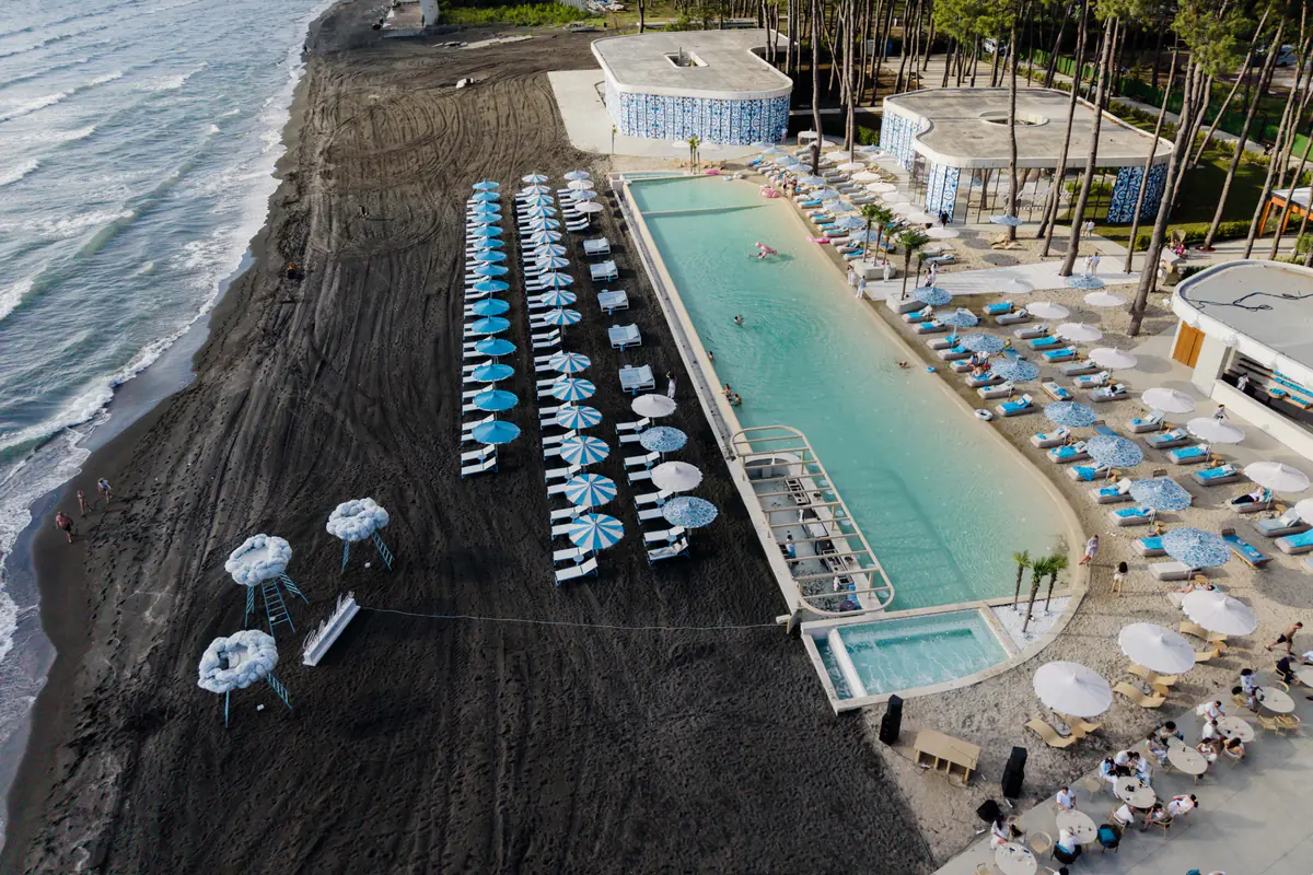 The club pool from above in July 2026, the loungers and the line of surf